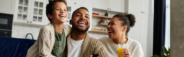 African american family laughing, holding glasses of orange juice. — Stock Photo