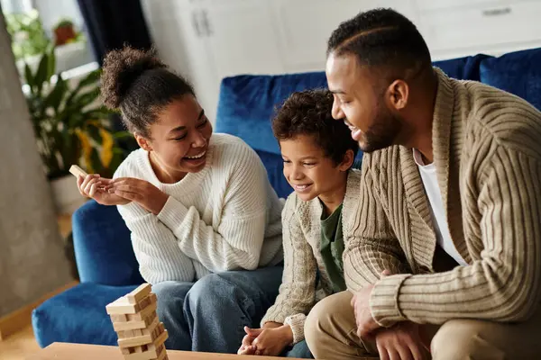A joyful African American family playing a game on the couch together. — Stock Photo