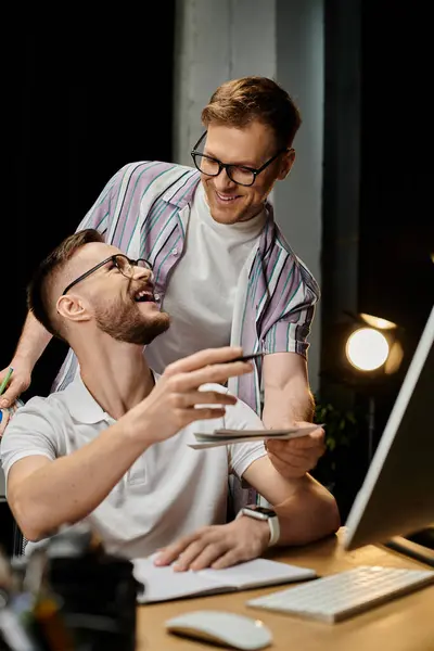 Two men in casual attire engaging with a laptop at a desk. — Stock Photo