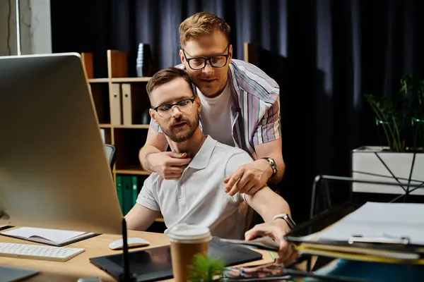 Two men explore a computer screen together in an office setting. — Stock Photo