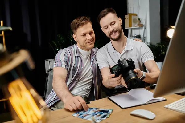 Двоє стильних, різноманітних чоловіків, які співпрацюють на проекті за столом з ноутбуком і камерою. — стокове фото