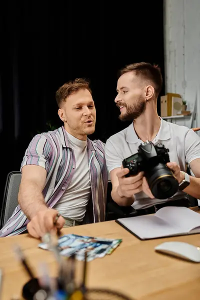 Two men in casual attire collaborating on a project with a camera on the table. — Stock Photo