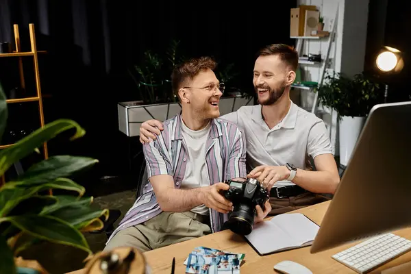 Zwei Männer, einer mit Laptop und der andere mit Kamera, arbeiten gemeinsam an einem Schreibtisch. — Stock Photo