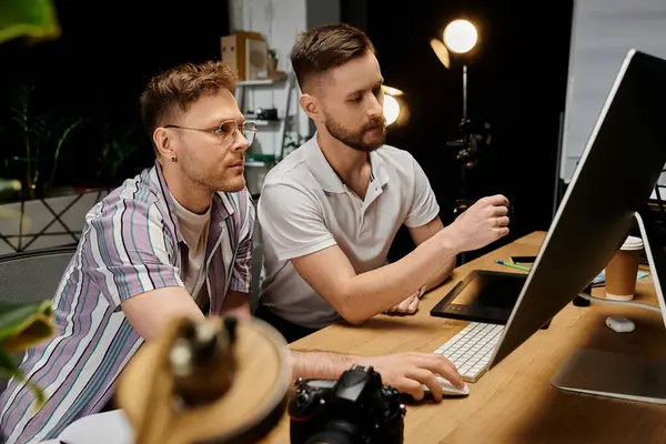 Two men engrossed in work on a laptop at a desk. — Stock Photo