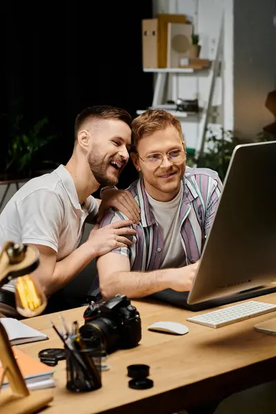 Two men in casual attire working together on a laptop at a desk. — Stock Photo