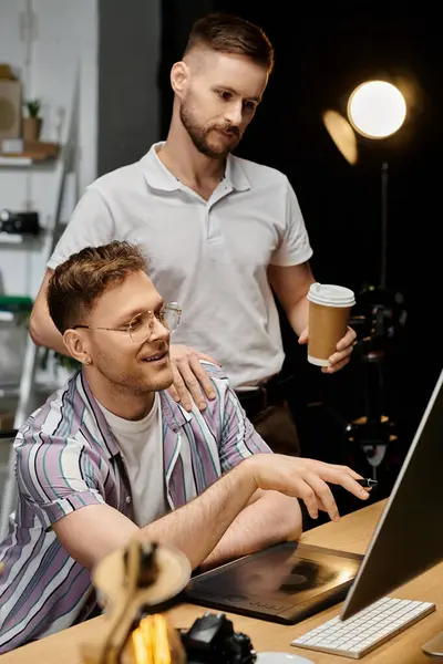 Um homem de traje aconchegante concentra-se no trabalho do laptop, seu parceiro segurando café. — Fotografia de Stock