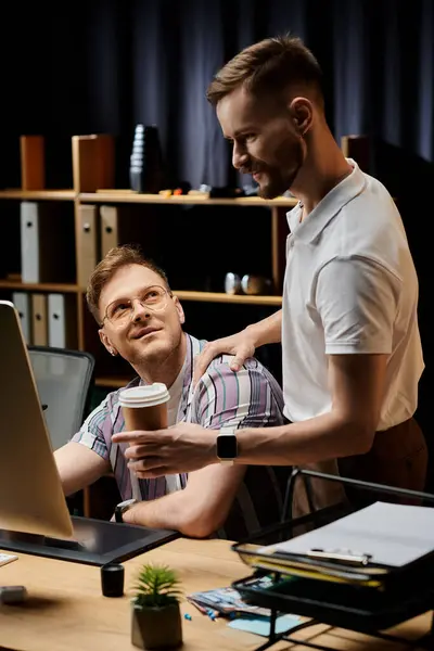 Due uomini amorevoli in abiti da lavoro seduti alla scrivania con una tazza di caffè. — Foto stock