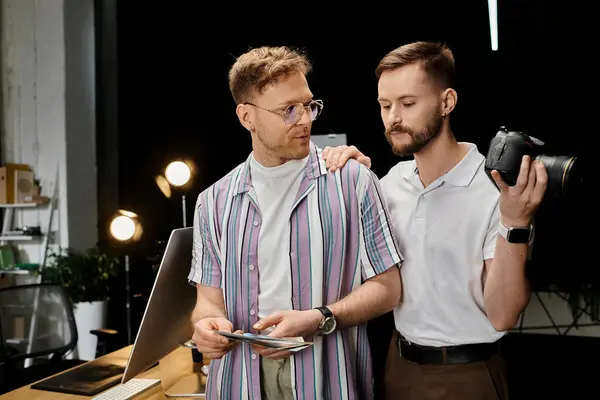 Two men in casual attire stand side by side in front of a laptop in an office setting. — Stock Photo