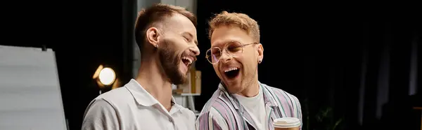 Two cheerful men collaboratively standing together in a workplace setting. — Stock Photo