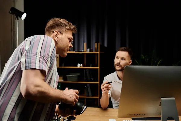 Two men in casual attire working together on a laptop at a table. — Stock Photo