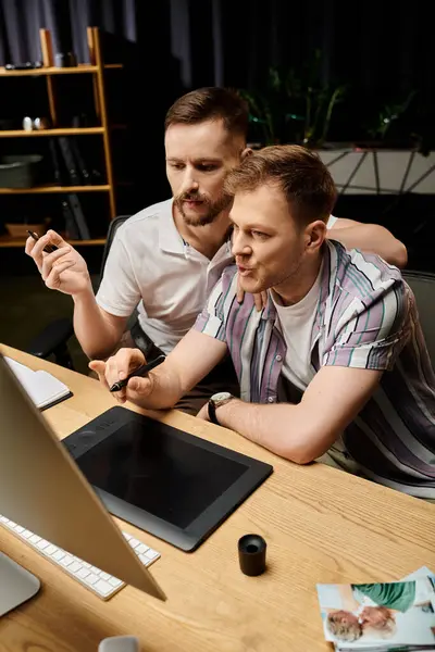 Two men in casual attire, focused on a laptop screen at a table. — Stock Photo