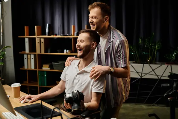 Man working at computer with camera with his partner. — Stock Photo