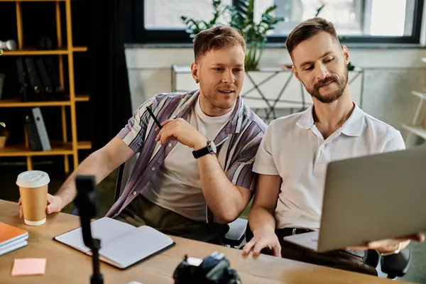 Zwei Männer in Freizeitkleidung arbeiten gemeinsam an einem Laptop an einem Tisch. — Stock Photo