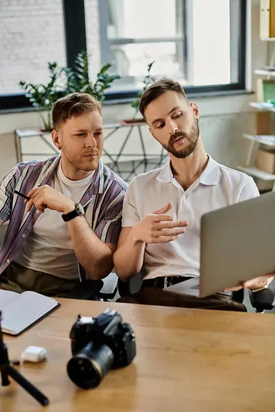 Two men in casual attire engrossed in laptop work together at a table. — Stock Photo