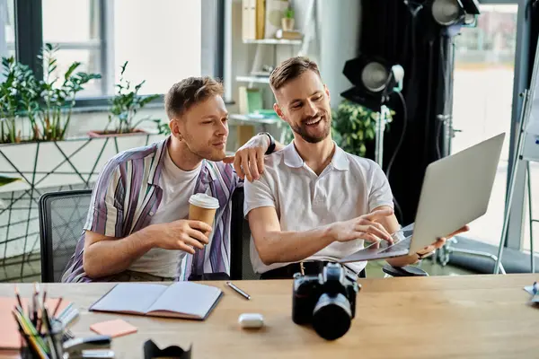 Dois homens de traje casual trabalham juntos em um laptop em uma mesa. — Fotografia de Stock