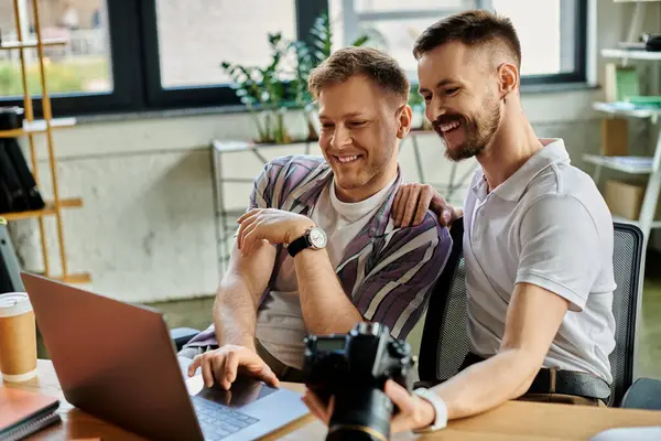 Two men in casual attire, smiling, focused on a laptop at a table. — Stock Photo