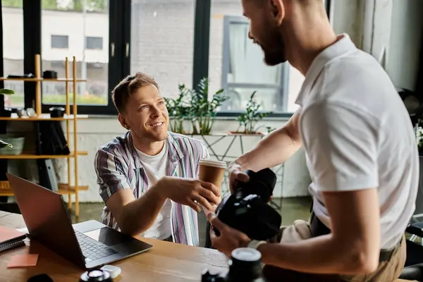 Two men in cozy outfits collaborating, camera in hand. — Stock Photo