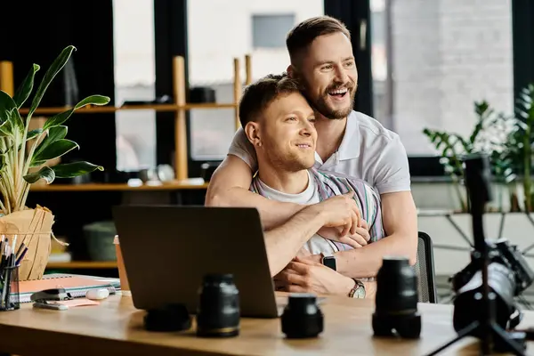 A man hugs another man in front of a laptop while working together. — Stock Photo