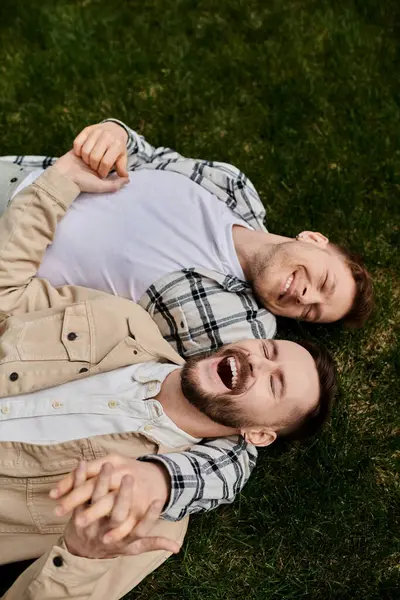 Two men in comfortable attire lying on lush green field. — Stock Photo