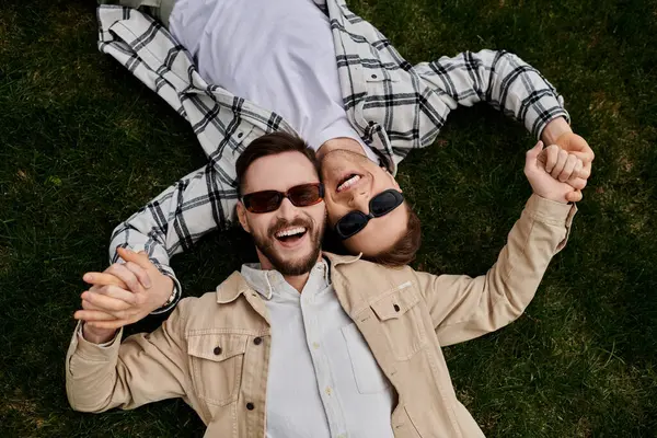 Deux hommes aimants en tenue confortable, couchés paisiblement sur l'herbe. — Photo de stock