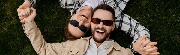 Two men in love, lounging on lush grass under the sky. — Stock Photo