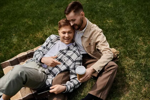 A couple of men relax on a blanket outdoors, enjoying a serene moment together. — Stock Photo