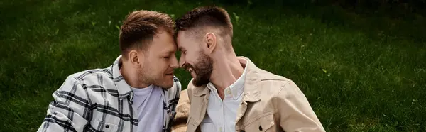 Two men in casual attire sitting closely, sharing a moment of happiness outdoors. — Stock Photo