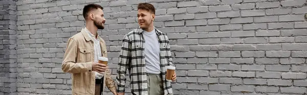 Due uomini in abbigliamento casual in piedi vicino al muro di mattoni. — Foto stock