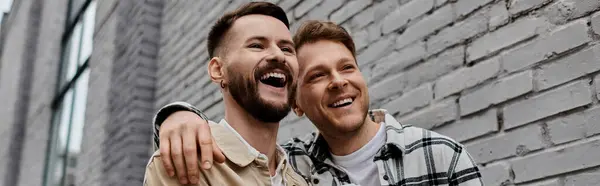 Dos hombres en atuendo casual de pie cerca de una pared de ladrillo. — Stock Photo