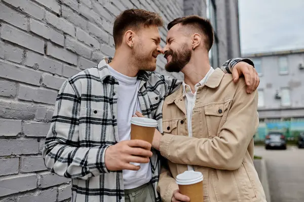 Due uomini in abbigliamento casual in piedi fianco a fianco vicino a un muro di mattoni intemperie. — Foto stock