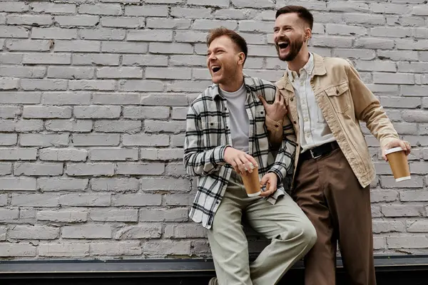 Two men enjoying a conversation beside a brick wall. — Stock Photo
