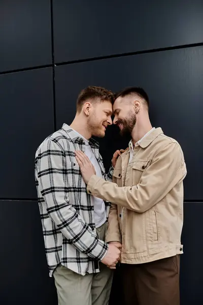 Dos hombres con atuendo casual de pie ante una pared negra. - foto de stock