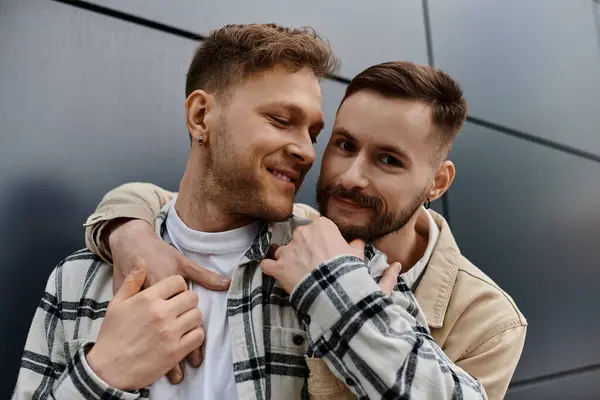 Dos hombres casualmente vestidos se paran uno al lado del otro cerca de un edificio, disfrutando de la compañía del otro.. — Stock Photo