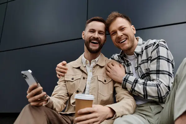 Two men in casual attire sitting closely outdoors. — Stock Photo