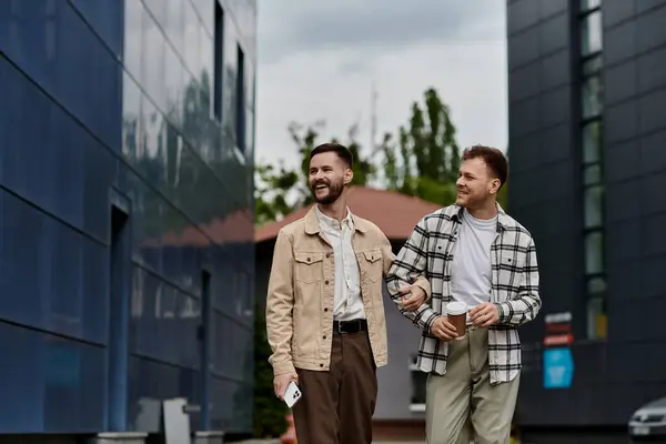 Two men dressed comfortably, standing outdoors in front of a building. — Stock Photo