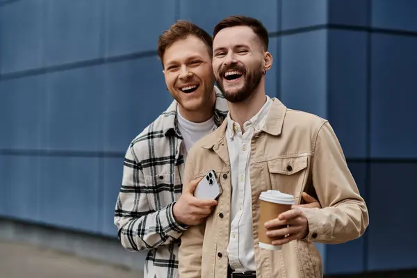 Zwei Männer in kuscheliger Kleidung stehen nebeneinander und halten Kaffeetassen in der Hand. — Stockfoto