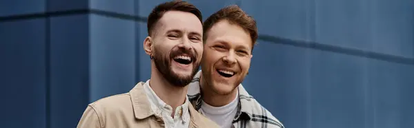 A happy gay couple in casual clothes standing next to each other outdoors. — Stock Photo