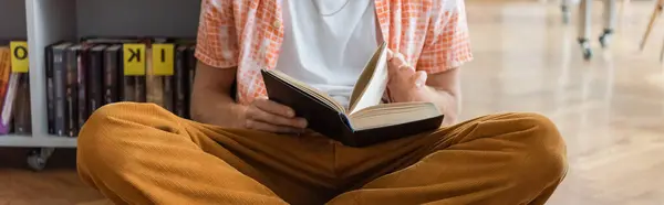 A person sitting on the floor, engrossed in reading a book. — Stock Photo
