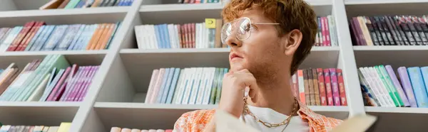 Man with glasses exploring books on bookshelf. — Stock Photo