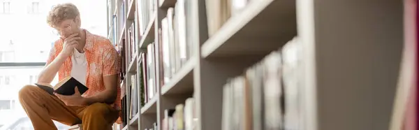 Красивый студент читает по сложенным книгам. — стоковое фото