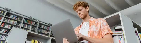 Studious young man with laptop in library. — Stock Photo