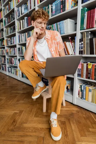 A man immersed in work on his laptop while sitting on a chair. — Stock Photo