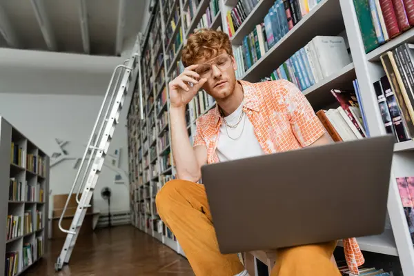 A man sits at a chair in front of a laptop computer. — Stock Photo