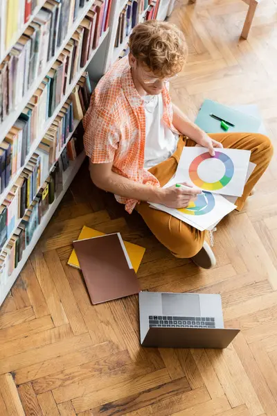 Una persona si siede davanti a una libreria, assorbita nella lettura e nello studio. — Foto stock