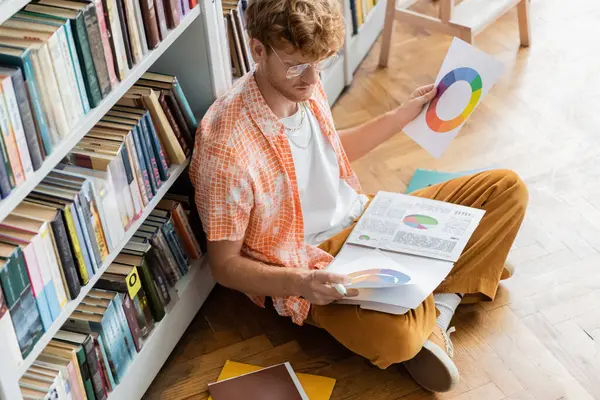 Молодой человек сидит на полу, погруженный в чтение книги. — стоковое фото