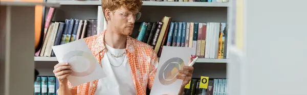 Man arranging papers in front of a bookshelf. — Stock Photo