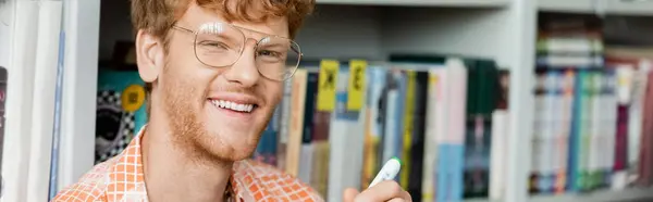 A bespectacled man gleefully holds a pen, symbol of creativity and knowledge. — Stock Photo