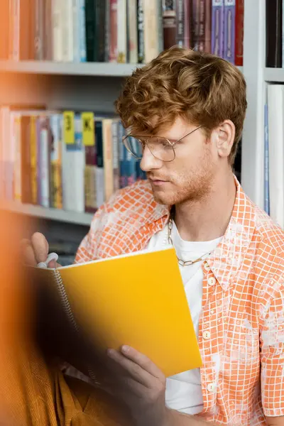 A man engrossed in a book at a library. — Stock Photo
