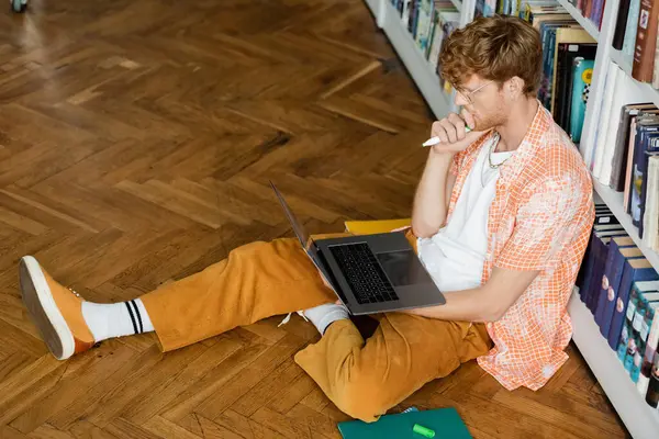 A man sitting on the floor, intensely focused on using a laptop. — Stock Photo
