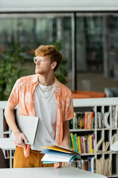 A man holding papers in front of a bookshelf. — Stock Photo